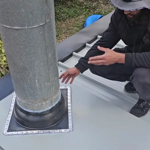 Close-up of a new flashing sealed around a flue on a metal roof