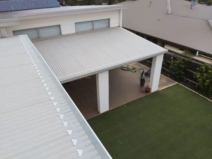New metal pergola roof with gutters over a backyard deck