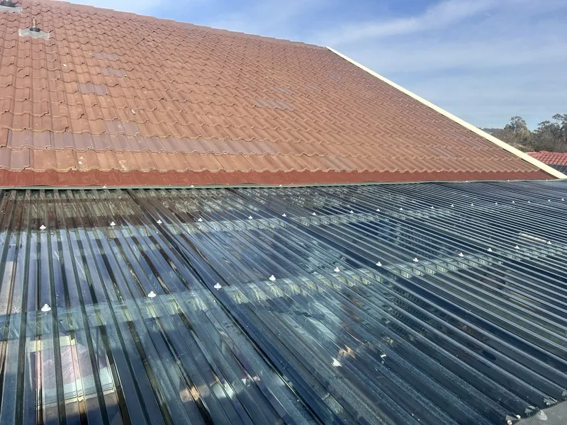 New clear polycarbonate roof over a deck below a terracotta tile roof