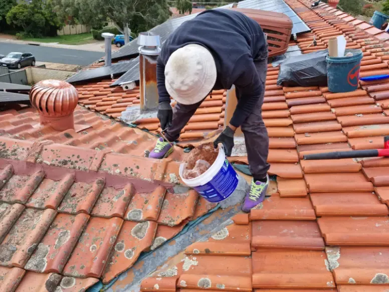 Roofer repointing ridge capping on a terracotta tile roof